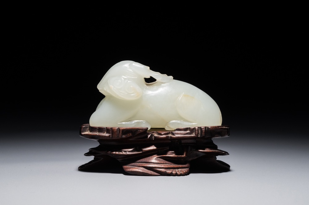 A Chinese jade carving of a ram on wooden base, 19th C.